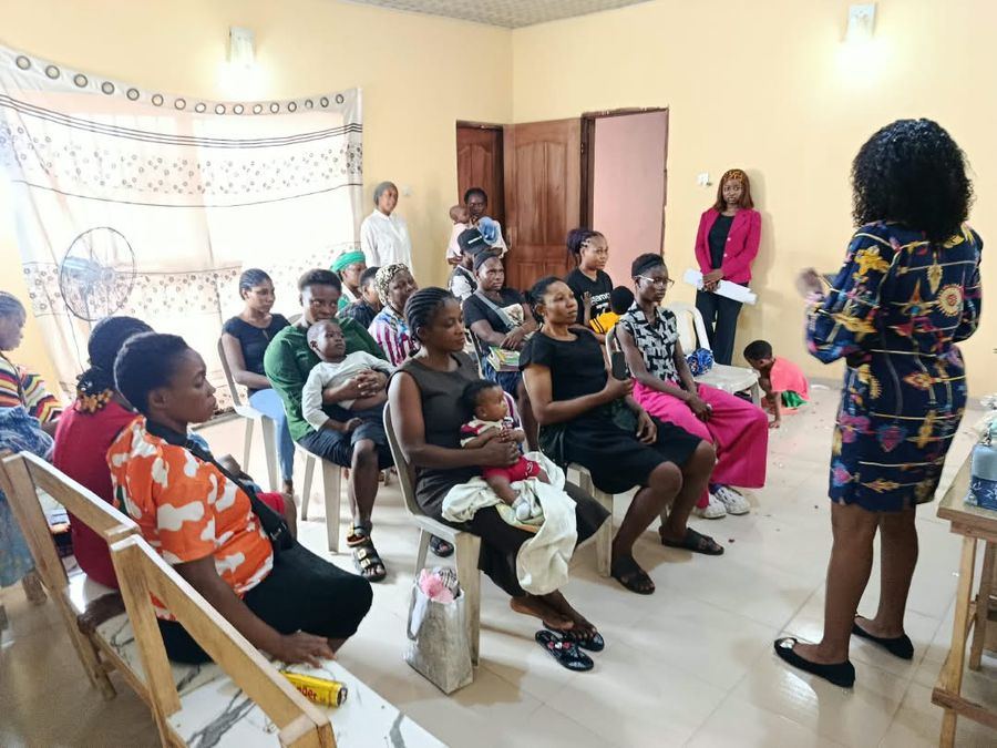 A staff member addressing parents, some holding babies, at a parents' forum