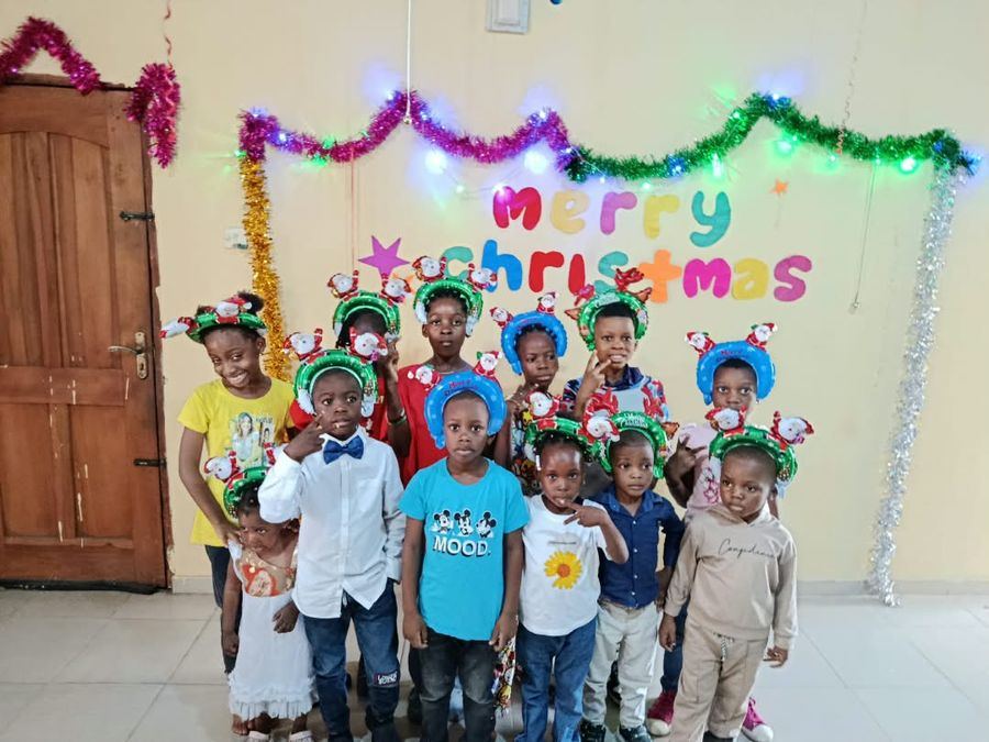 Pupils in festive headbands in front of a Merry Christmas display