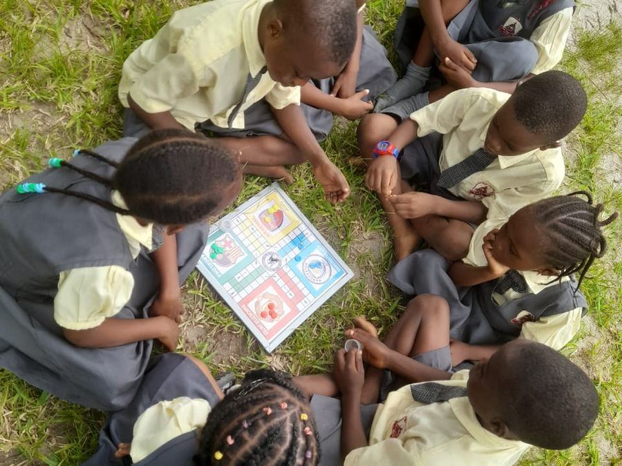 Pupils sitting in a circle on the grass playing a board game