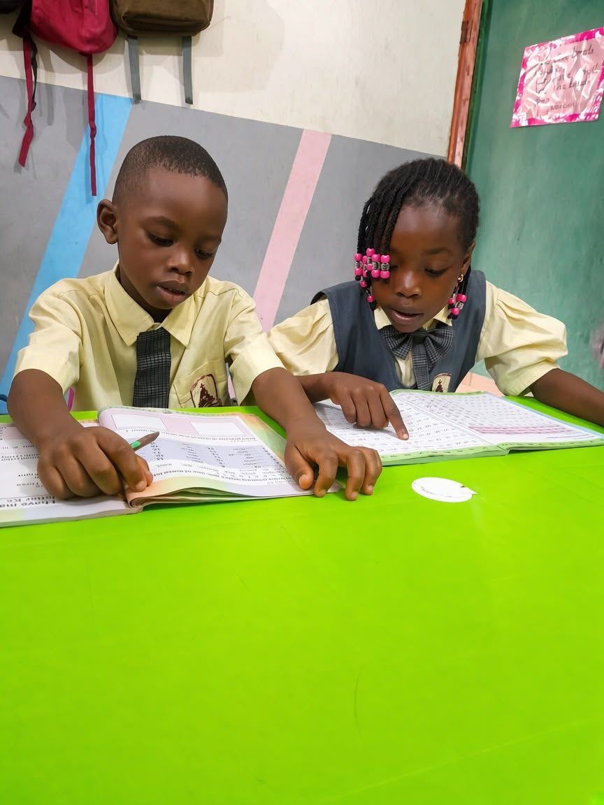 Two pupils in school uniform reading together at their desk